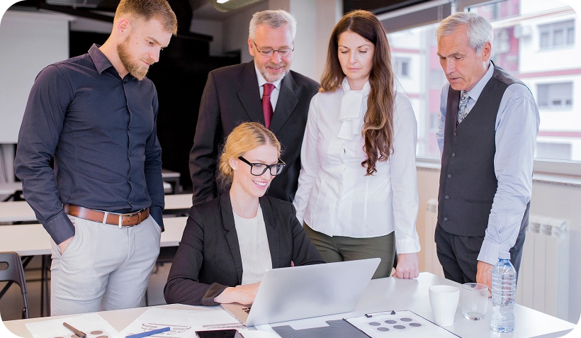 Team van zakelijke professionals verzameld rond een laptop tijdens een logistieke planningsvergadering in een moderne kantoorvergaderruimte.